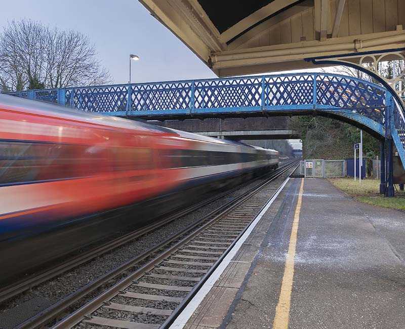 Long exposure of train going under a pedestrian bridge.